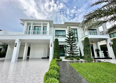 Modern white two-story house with large driveway and garden