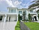 Modern white two-story house with large driveway and garden