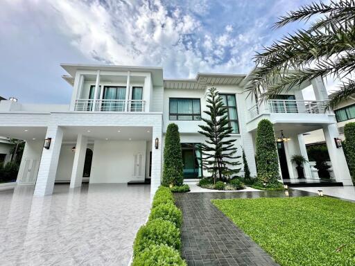 Modern white two-story house with large driveway and garden