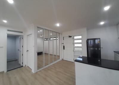 Modern kitchen with sleek white cabinetry, mirrored storage doors, and light hardwood flooring