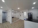 Modern kitchen with sleek white cabinetry, mirrored storage doors, and light hardwood flooring