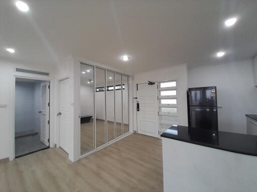 Modern kitchen with sleek white cabinetry, mirrored storage doors, and light hardwood flooring