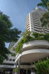 High-rise residential building with green landscaping and covered parking