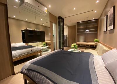 Modern bedroom with a large bed, TV, and a small seating area