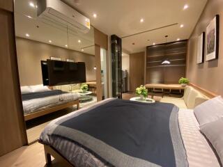 Modern bedroom with a large bed, TV, and a small seating area