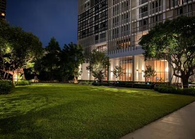 Modern apartment building with well-lit green lawn at night