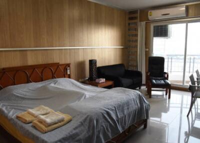 Bedroom with bed, seating area, air conditioner, and balcony access