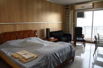 Bedroom with bed, seating area, air conditioner, and balcony access