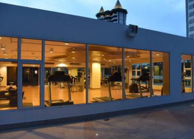 View of a modern gym with large windows showcasing various exercise equipment.