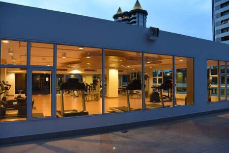 View of a modern gym with large windows showcasing various exercise equipment.