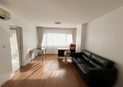 Spacious living room with natural light, sofa, and desk