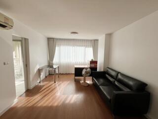 Spacious living room with natural light, sofa, and desk