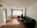 Spacious living room with natural light, sofa, and desk