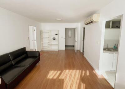 Spacious living room with wooden flooring and black sofa