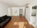 Spacious living room with wooden flooring and black sofa