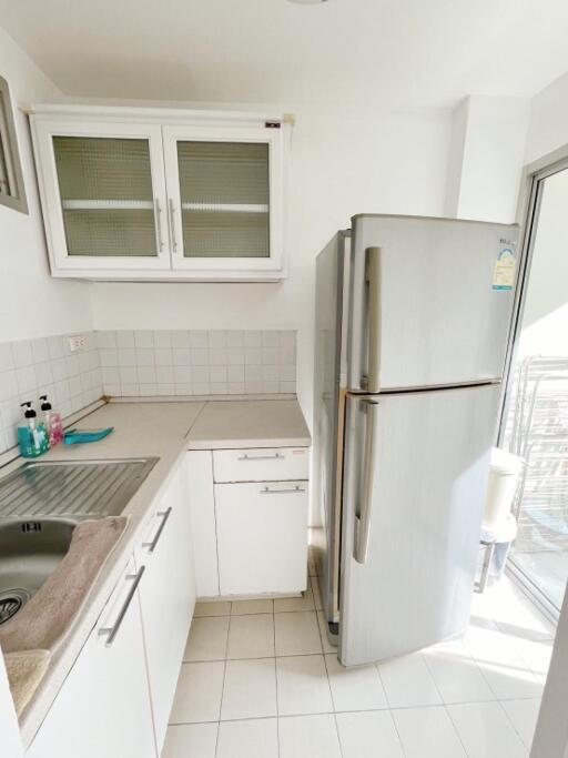 Compact modern kitchen with white cabinetry and stainless steel refrigerator