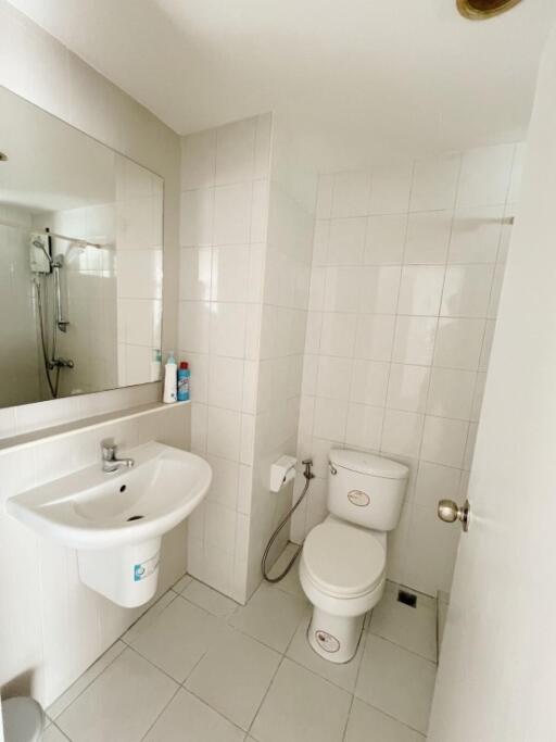 Clean white bathroom with a toilet, sink, mirror, and shower