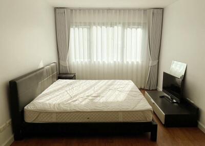 Spacious bedroom with a large bed, bedside table, and mounted television