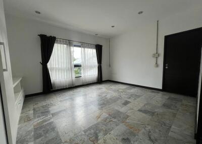 Spacious empty living room with tiled flooring and large window with curtains