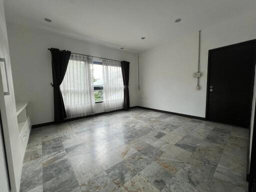 Spacious empty living room with tiled flooring and large window with curtains