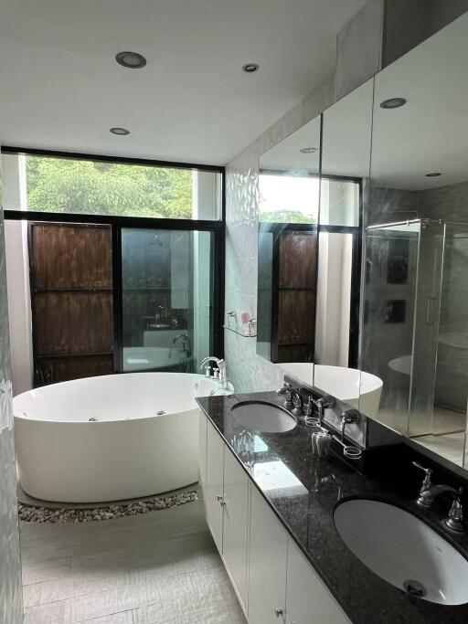 Modern bathroom with double sinks, large bathtub, and shower