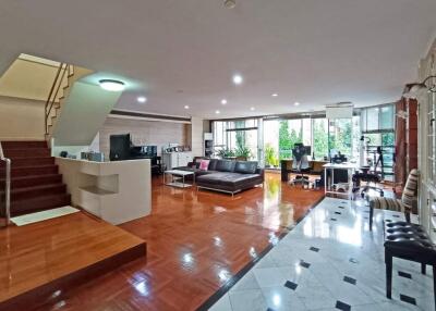 Spacious living room with hardwood floors, staircase, and large windows