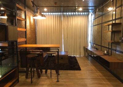 Industrial-style living room with wooden flooring, bar stools, and shelves