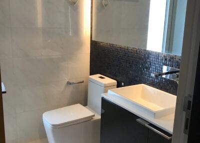 Modern bathroom with a large mirror, white sink, and toilet