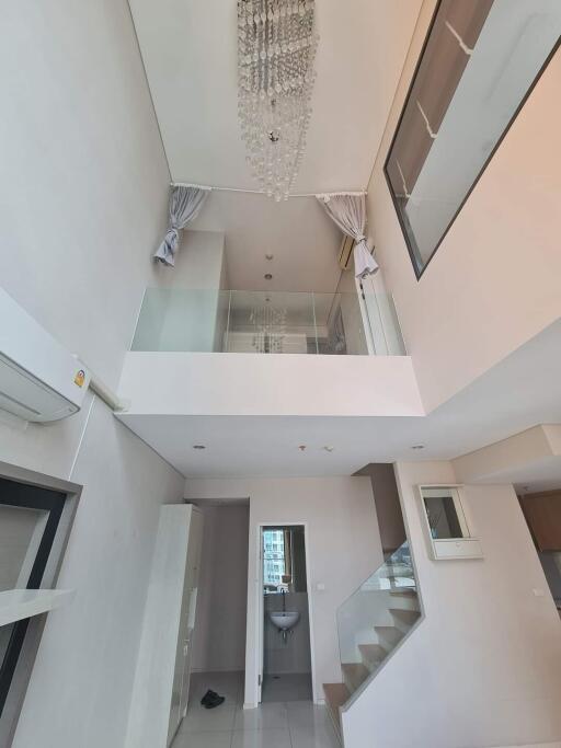 Modern living area with high ceiling and chandelier