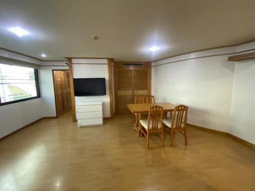 Spacious living room with wooden floor, dining table, TV, and large window