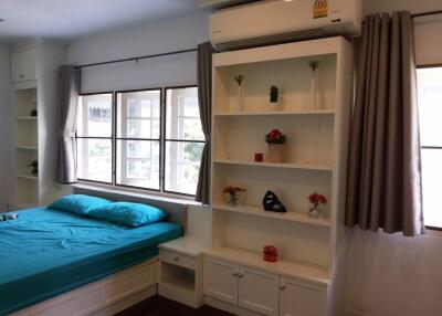 Bright bedroom with teal bedding, a large window, white shelves, and an air conditioner