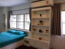 Bright bedroom with teal bedding, a large window, white shelves, and an air conditioner