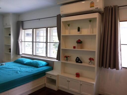 Bright bedroom with teal bedding, a large window, white shelves, and an air conditioner