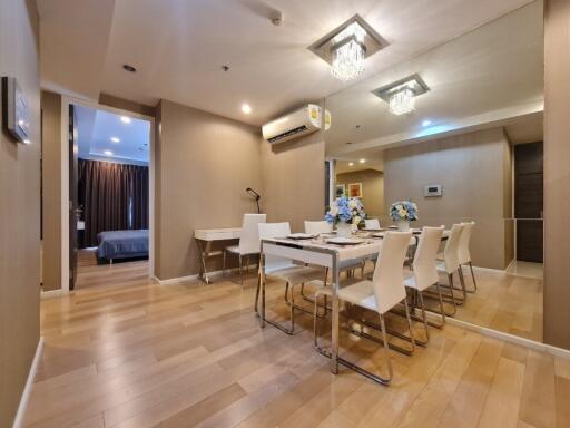 Modern dining area with wooden floors, a long table, and white chairs.