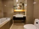 Modern bathroom with beige tiles, a bathtub, a washbasin, and a toilet