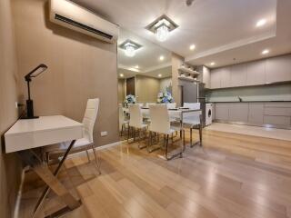 Modern dining area with white chairs, table, and kitchen in the background