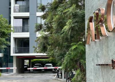 Entrance to a modern apartment building with trees and parking area