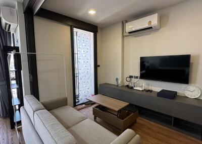 Modern living room with sofa, wall-mounted TV, and air conditioning