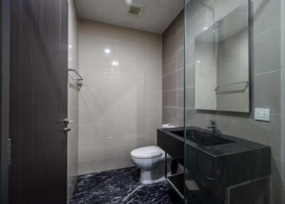 Modern bathroom with glass shower partition and black countertop