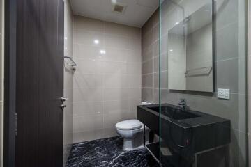 Modern bathroom with glass shower partition and black countertop