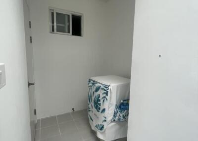 Small laundry area with a washing machine, tiled floor, and a small window.