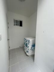 Small laundry area with a washing machine, tiled floor, and a small window.