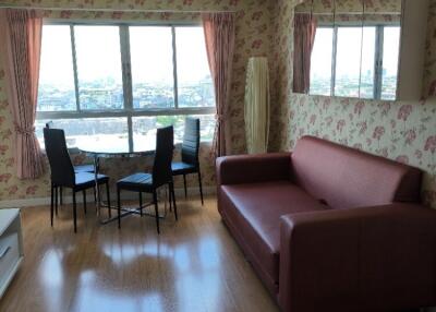 Living room with a red sofa, dining table, large windows, and floral wallpaper