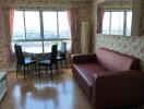 Living room with a red sofa, dining table, large windows, and floral wallpaper