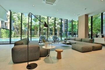 Spacious modern living room with large windows, grey sofas, and a view of a pool