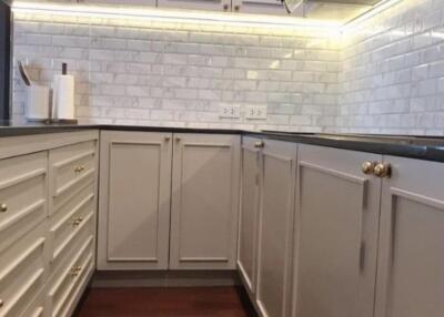 Modern kitchen with white cabinets, backsplash, and wooden floor