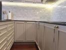 Modern kitchen with white cabinets, backsplash, and wooden floor