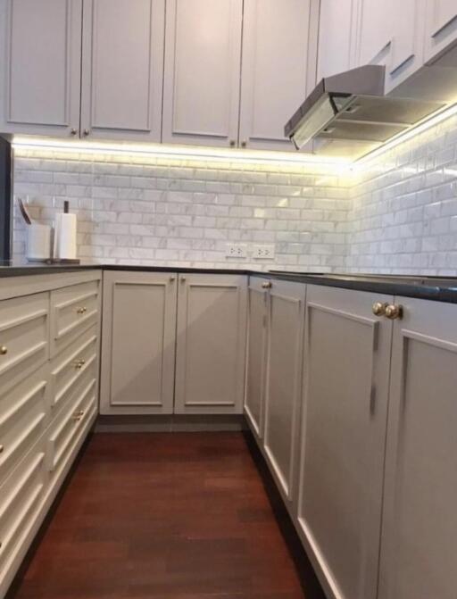 Modern kitchen with white cabinets, backsplash, and wooden floor