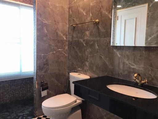 Modern bathroom with marble tiles, vanity, and toilet