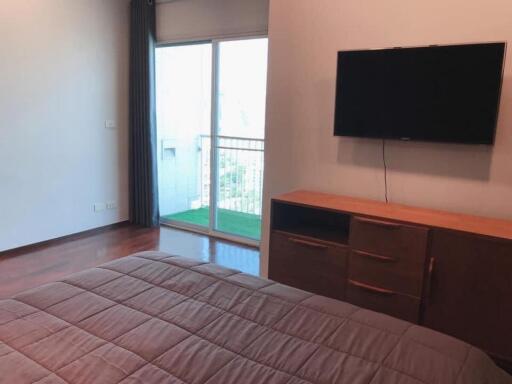 Bedroom with balcony access and mounted television